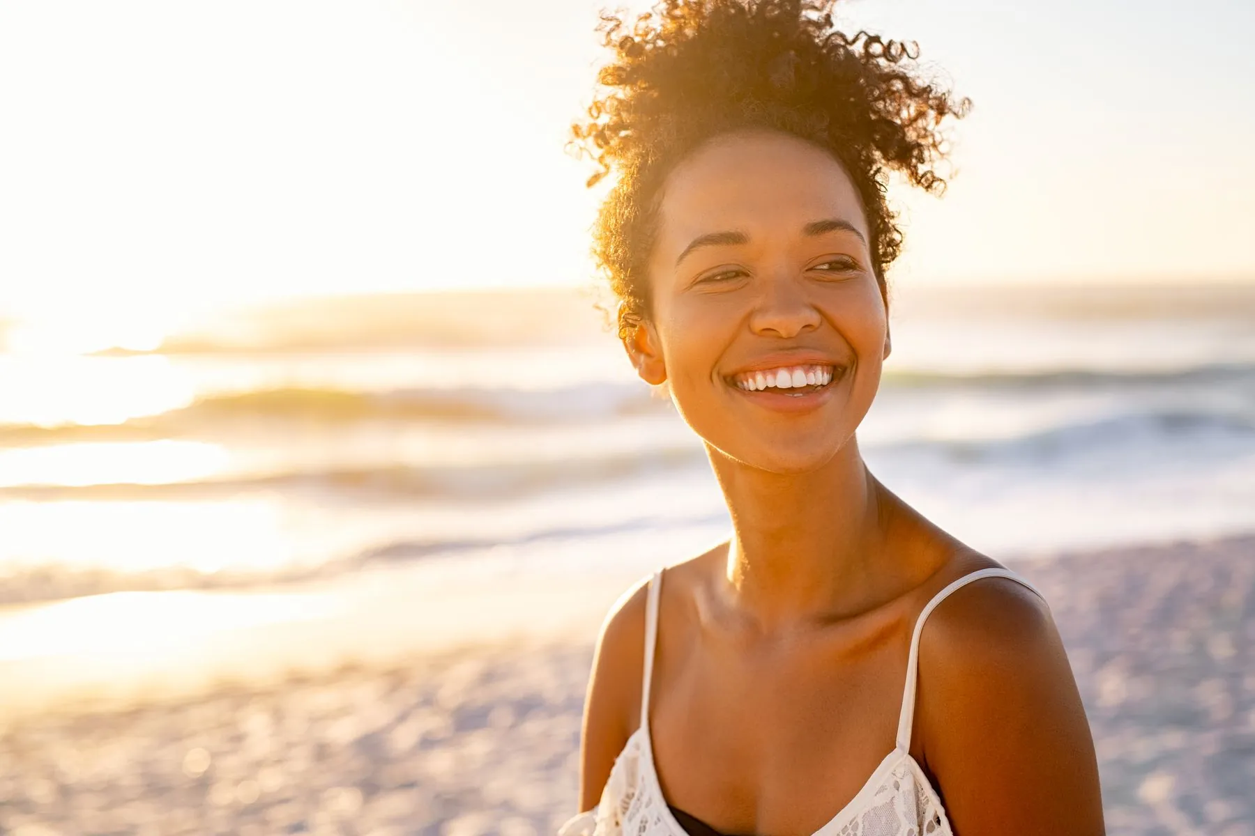 陽光海灘上微笑的女性，身穿白色細肩帶上衣，象徵 ya!smile 醫師信賴的隱形矯正微調品牌精神